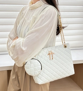 Close-up of quilted white leather barrel bag with gold chain and flamingo charm detail