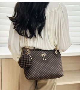 Detail of brown cylinder bag featuring geometric prints and gold swan metal pendant