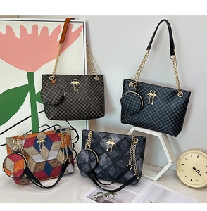 Detail of stylish twill cylinder bags with gold chain straps and bird logo charms