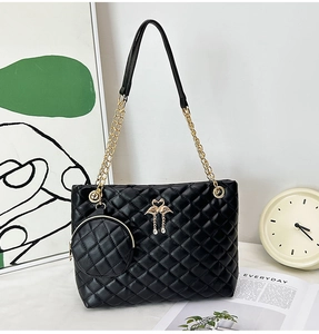 Detail of black quilted barrel bag with gold swan buckle and round coin purse charm