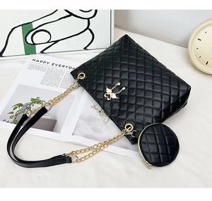 Detail of black quilted barrel bag with gold butterfly clasp and round coin purse accessory