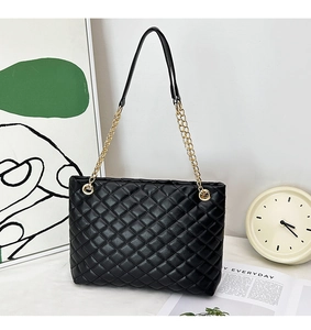 Detail of black quilted faux leather surface with gold chain strap on a designer tote