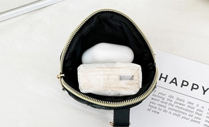 Interior view of black quilted cylinder bag showing capacity for earphones and tissue
