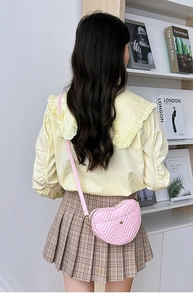 Detailed close-up of pink heart-shaped crossbody bag with V-quilted texture and gold logo