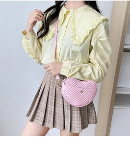 Detail of pink heart-shaped crossbody bag with V-quilted faux leather and gold hardware
