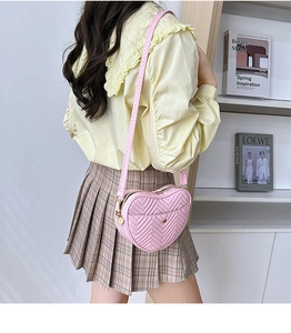 Detail of pink heart-shaped crossbody bag featuring V-quilted stitching and gold hardware