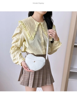 Close-up of heart-shaped crossbody bag with white quilted PU and gold metal buckle