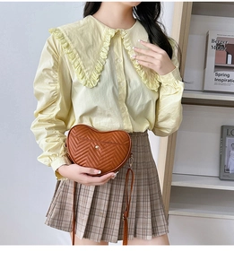 Brown heart-shaped quilted crossbody bag with V-shaped stitching shown on model