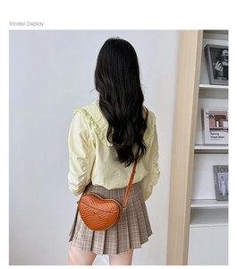 Rear view of model wearing a caramel heart-shaped crossbody bag with chevron quilting