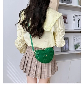 Close-up of heart-shaped green crossbody bag with V-quilted faux leather and gold hardware
