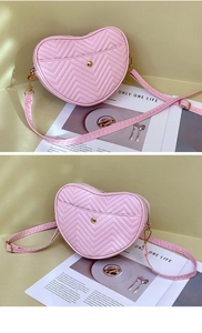 Detail of pink heart-shaped crossbody bag featuring chevron quilting and gold metal hardware