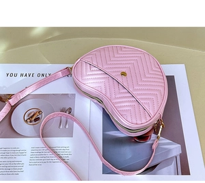 Close-up of pink quilted leather heart-shaped crossbody bag with gold metal buckle