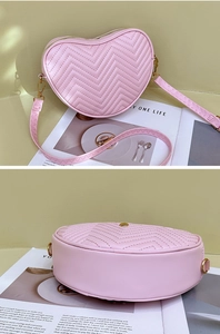 Detail of pink heart-shaped crossbody bag featuring chevron quilting and gold zippers