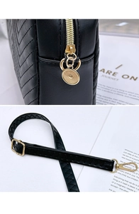 Close-up of black V-quilted faux leather bag with gold metal hardware and zipper detail