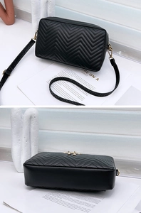 Detail view of black V-quilted crossbody bag with gold zipper and leather strap