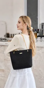 Detail of black quilted tote bag featuring gold chain strap and elegant chevron stitching