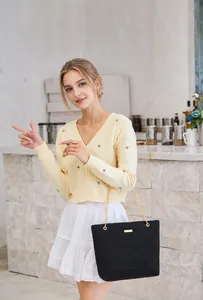 Chic black quilted shoulder bag with gold chain strap shown on model in modern interior