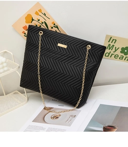 Top view of black quilted leather tote bag with gold chain straps and V-shaped stitching
