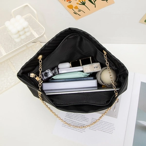 Quilted black leather tote bag with gold chains showing spacious inner storage capacity