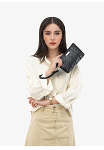 Close-up of black quilted leather handbag with silver logo plate and wrist strap