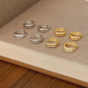 Chic gold and silver hoop earrings with zircon pavé displayed on a book edge