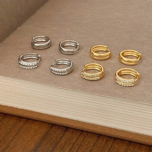 Detail shot of gold and silver hoop earrings with micro-paved cubic zirconia on book edge