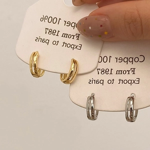 Detail of minimalist copper hoop earrings in gold and silver finish on display cards