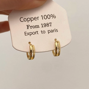 Close-up of golden double-hoop earrings made from 100 percent copper on display card