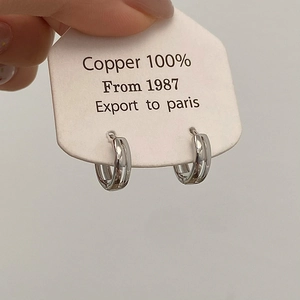 Detail of silver double-layered round earrings made of 100% copper on a white product card