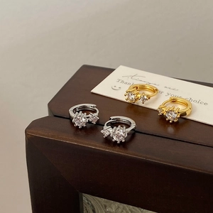 Close-up of gold and silver huggie earrings with sparkling round cubic zirconia stones