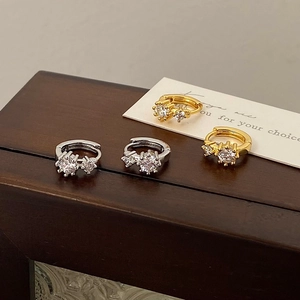 Minimalist silver and gold cubic zirconia hoop earrings displayed on a dark wooden box edge