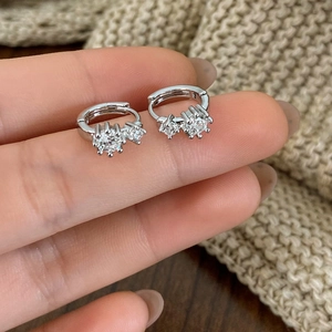 Macro shot of silver metal hoop earrings with sparkling cubic zirconia in a hand