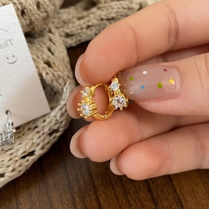 Close-up of gold plated hoop earrings with sparkling cubic zirconia on wood background