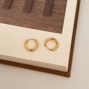Detail of 18k gold plated hoop earrings with high polish finish on a book edge