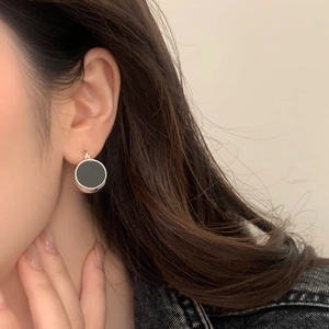 Close-up of French retro round earrings with silver frame and black matte center disc