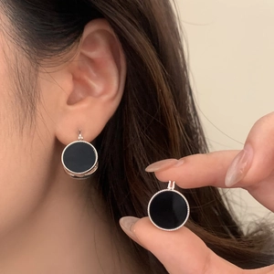 Close-up of vintage round earrings featuring black inlay and milgrain silver edges