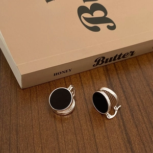 Close-up of retro silver hoop earrings with black onyx inlay and beaded texture detail