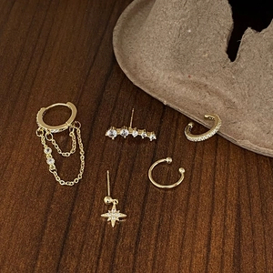 Detail of 5-piece gold star and moon stud earring set with zircons on wooden background