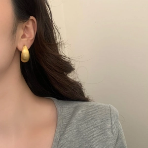 Gros plan de boucles d'oreilles goutte d'or élégantes avec finition mate brossée
