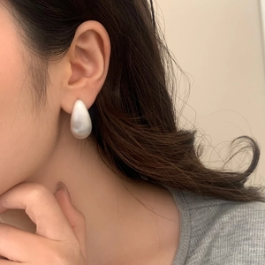Élégantes boucles d'oreilles goutte dorées avec finition satinée portées à l'oreille