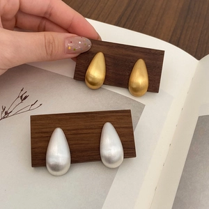 Vue détaillée des boucles d'oreilles goutte en or et argent avec finition brossée