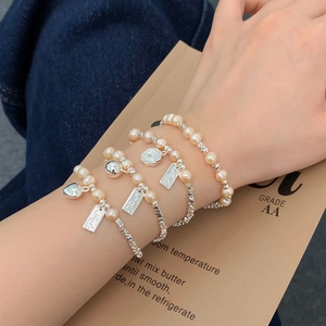 Detail eines vierteiligen Armband-Sets mit rosa Perlen und silbernen Herzanhängern