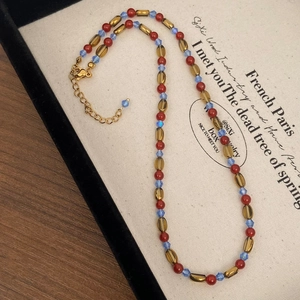 Detail of red agate style beaded necklace with lobster clasp and golden chain adjustment