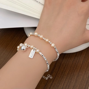 Elegantes mehrlagiges Perlenarmband mit Silberperlen und Herzanhänger am Handgelenk