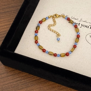Macro detail of red agate beads and blue crystals with a golden lobster clasp on a display
