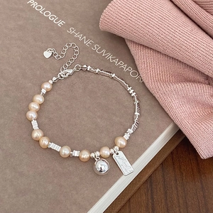 Detail von Süßwasserperlenarmband mit silbernen Würfelperlen und Herzanhänger auf Buch
