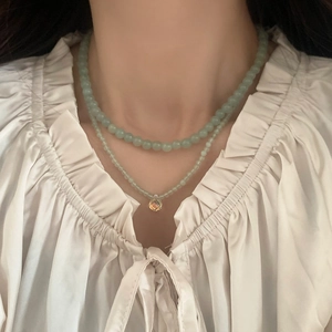 Double-layered beaded necklace with light green stones and a yellow drop pendant