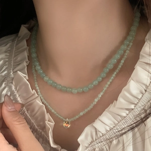 Macro shot of double-layered light green beaded necklace with teardrop pendant