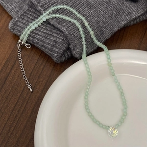 Detailed shot of mint green beaded necklace with a clear faceted crystal pendant charm