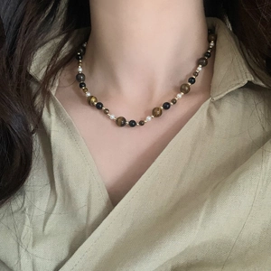Tiger eye stone beaded necklace with pearls and black agate beads on linen background